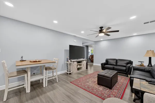 a kitchen with stainless steel appliances kitchen island granite countertop a refrigerator a stove a sink a dining table and chairs with wooden floor