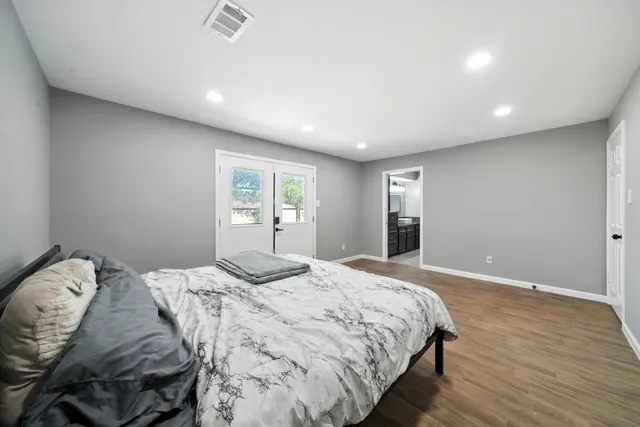 a bedroom with a large bed and wooden floor