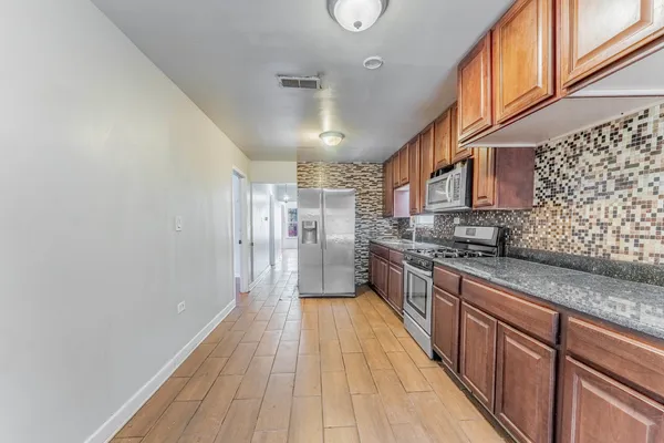a large kitchen with stainless steel appliances granite countertop a lot of counter space and wooden floor