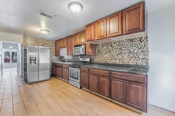 a kitchen with stainless steel appliances granite countertop a refrigerator and wooden cabinets
