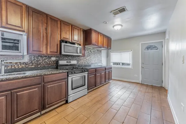 a kitchen with stainless steel appliances granite countertop a stove cabinets and entryway