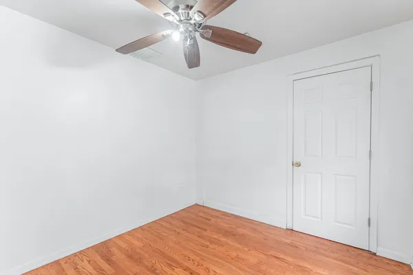 an empty room with wooden floor closet and fan