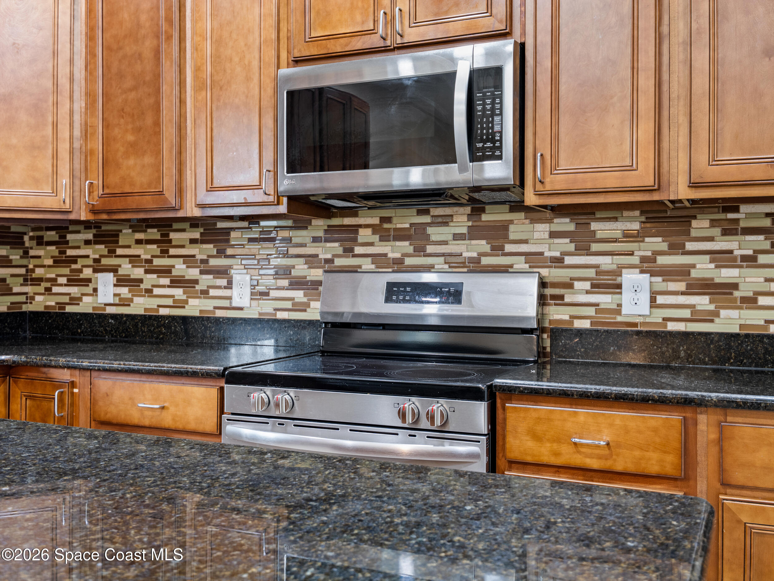 2246 Warwick Road Melbourne, FL 32935 - Photo 12 of 40 a kitchen with stainless steel appliances granite countertop a stove and a microwave