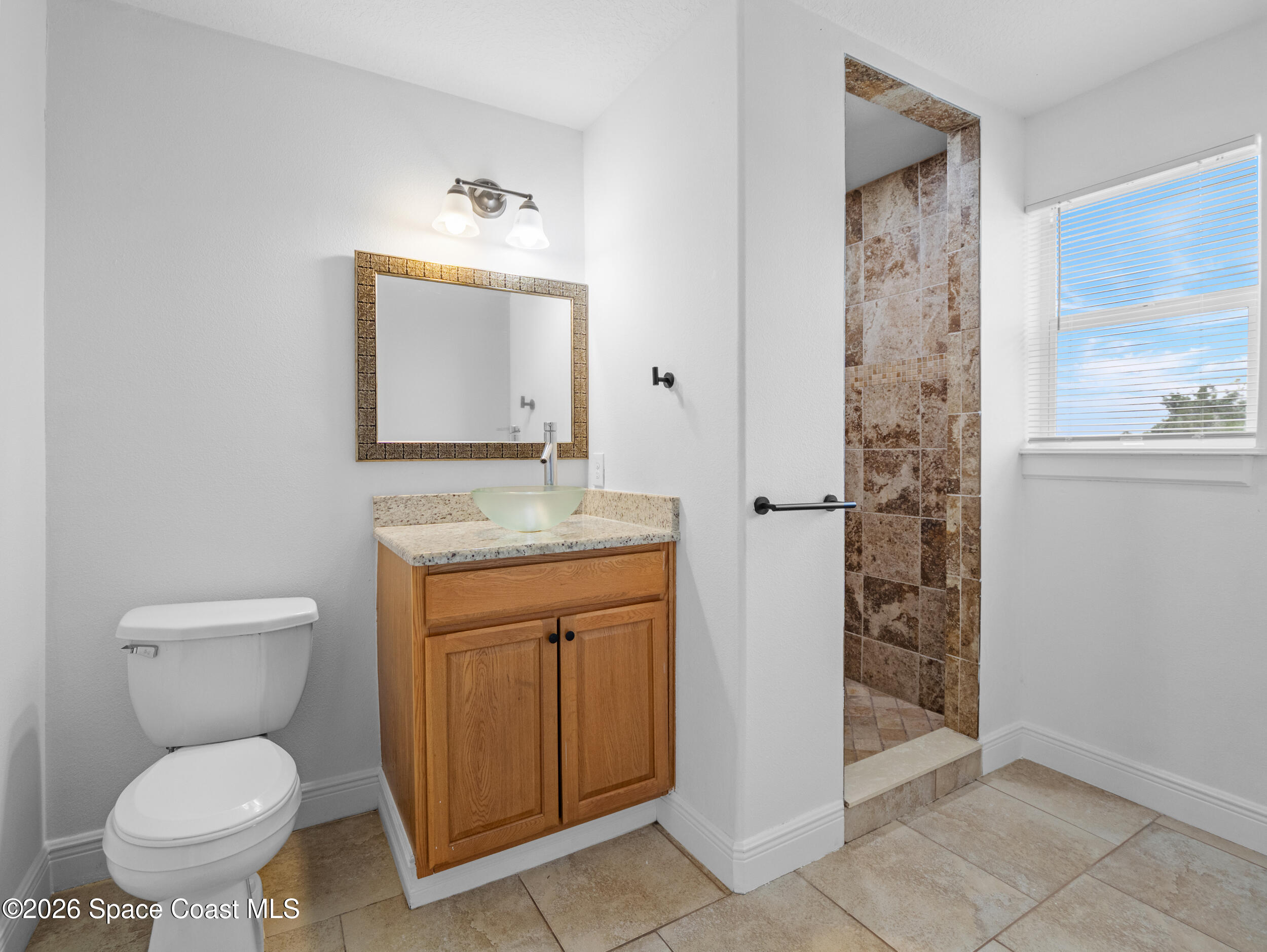 2246 Warwick Road Melbourne, FL 32935 - Photo 29 of 40 a bathroom with a granite countertop toilet sink and mirror