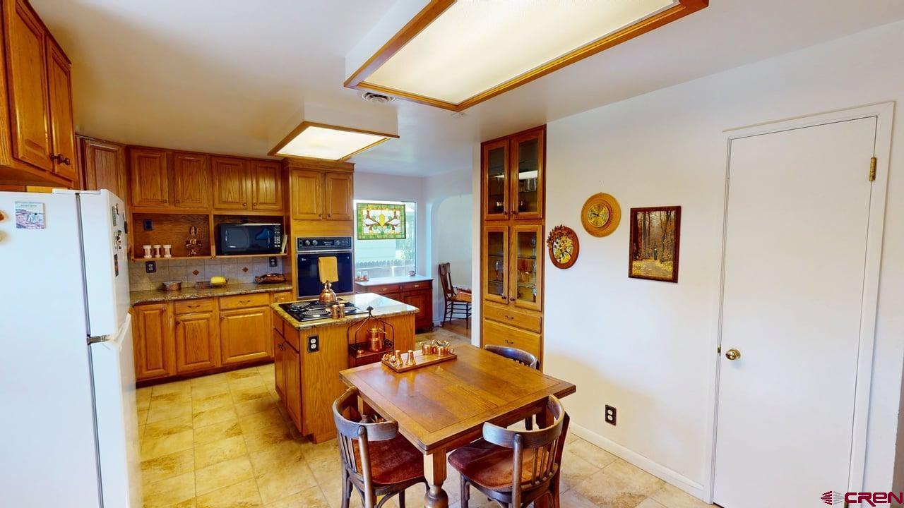 96 El Rio Drive Alamosa, CO 81101 - Photo 6 of 18 a kitchen with stainless steel appliances granite countertop a refrigerator a stove top oven a dining table and chairs with wooden floor