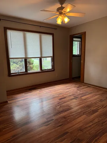 a view of an empty room with wooden floor and a window