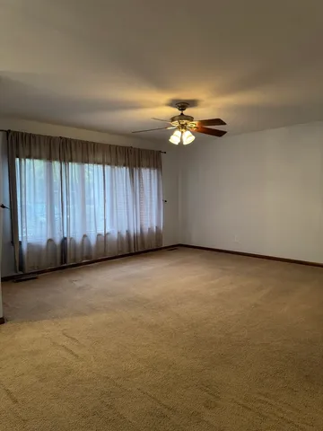 an empty room with a chandelier fan and windows