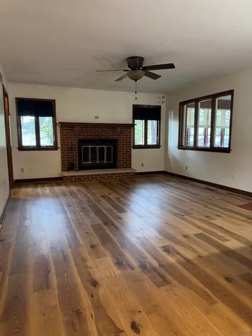 an empty room with wooden floor fireplace and windows