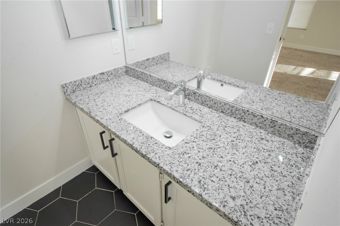 1468 Reef Ridge Court Las Vegas, NV 89128 - Photo 13 of 22 Double vanity featuring sleek granite counters, modern cabinetry, and bold hexagonal floor tiles.