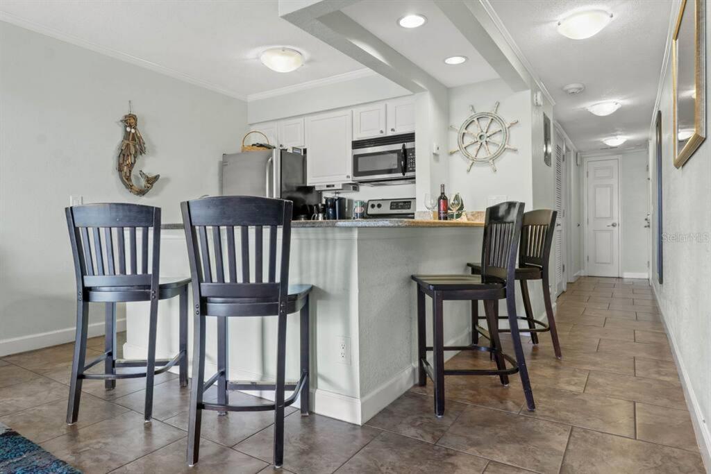 2506 North Rocky Point Drive, Unit 202 Tampa, FL 33607 - Photo 3 of 17 a kitchen with stainless steel appliances kitchen island granite countertop a dining table chairs and a refrigerator