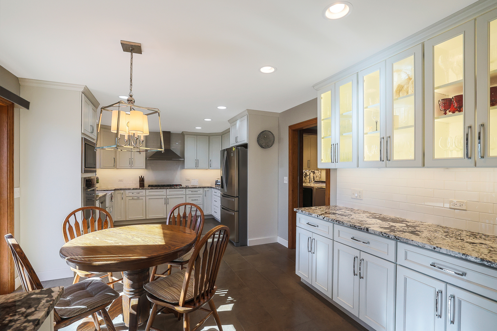 437 High Road Cary, IL 60013 - Photo 8 of 48 a large kitchen with granite countertop a stove a sink a dining table and chairs