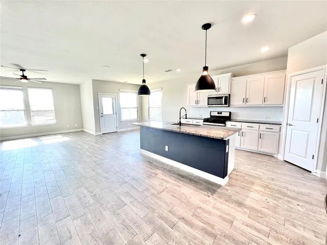 a kitchen with stainless steel appliances granite countertop a sink a stove and a wooden floors