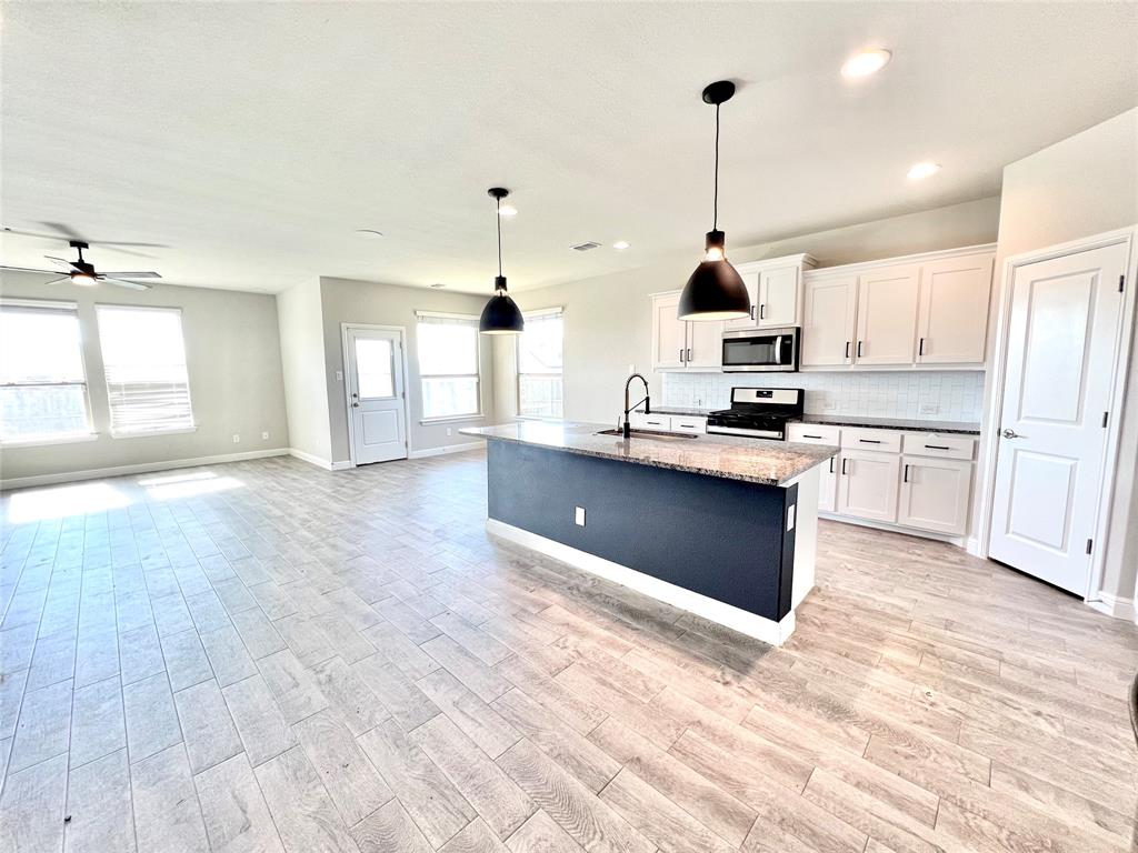 1600 Reed Drive Krum, TX 76249 - Photo 13 of 28 a kitchen with stainless steel appliances granite countertop a sink a stove and a wooden floors