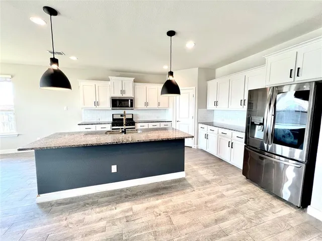 a kitchen with stainless steel appliances granite countertop a refrigerator a stove a microwave and a sink