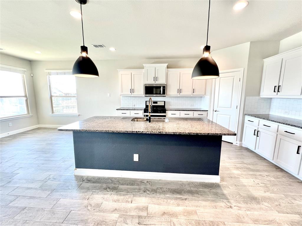 1600 Reed Drive Krum, TX 76249 - Photo 15 of 28 a kitchen with kitchen island granite countertop a sink a stove and a window