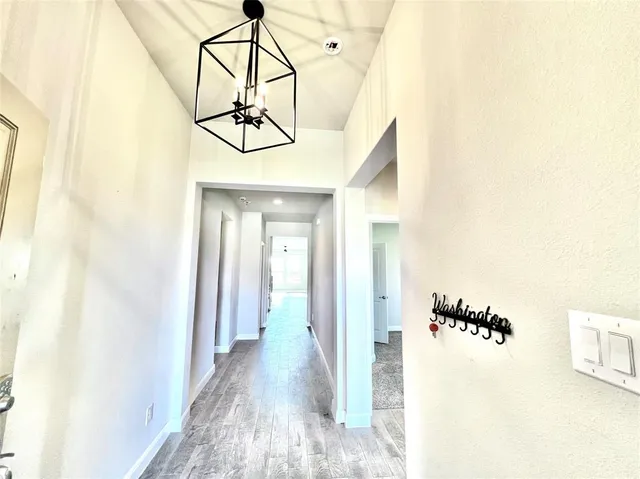 a view of a hallway with wooden floor and dining room