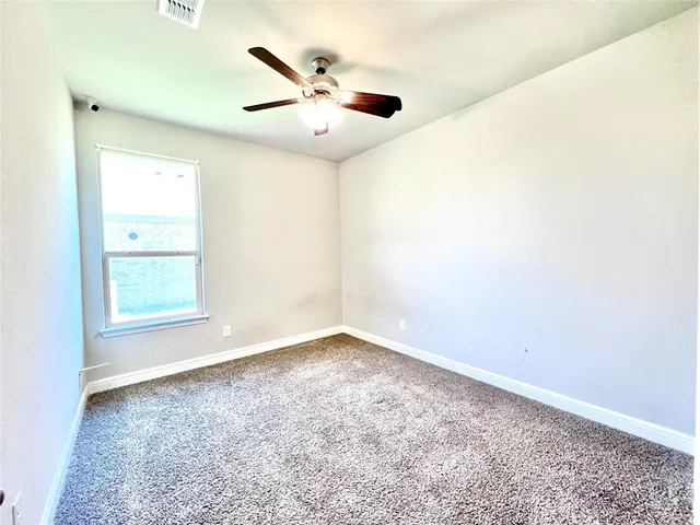 an empty room with a window and a ceiling fan