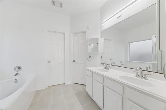 a spacious bathroom with a bathtub sink double and mirror