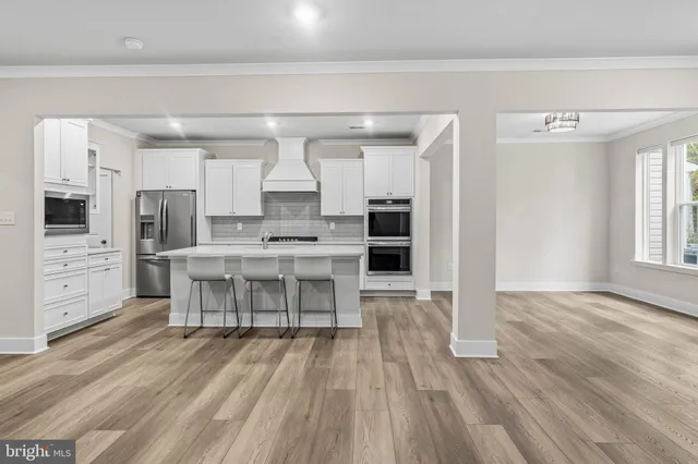 a open kitchen with white cabinets and wooden floor