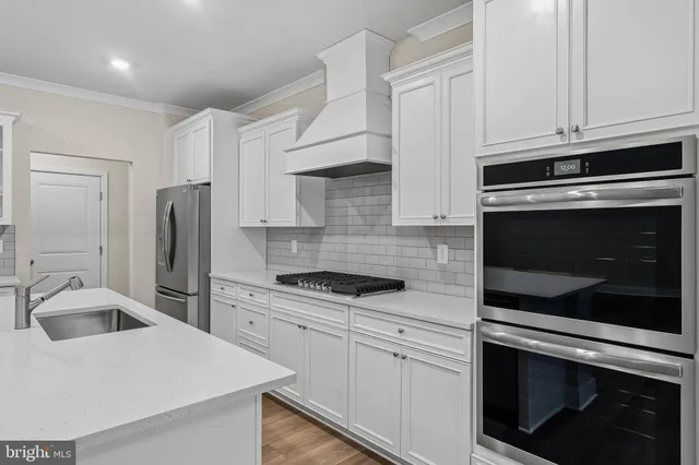 a kitchen with granite countertop white cabinets and stainless steel appliances