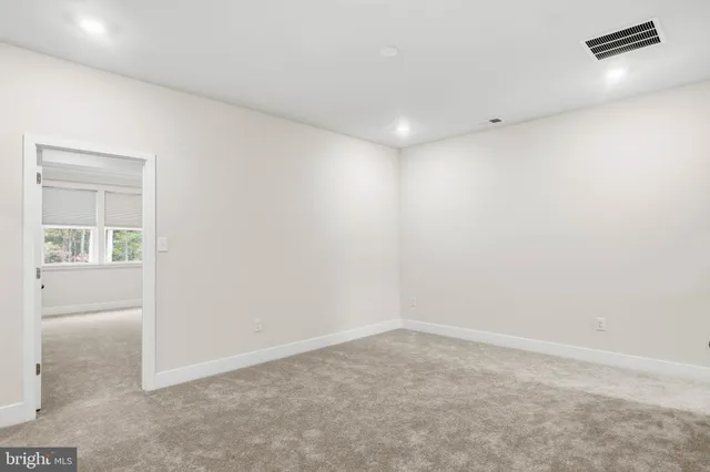 an empty room with windows and refrigerator