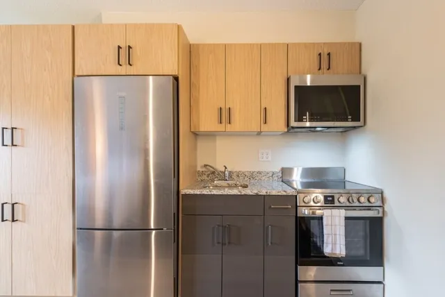 a kitchen with stainless steel appliances granite countertop a refrigerator and a stove top oven