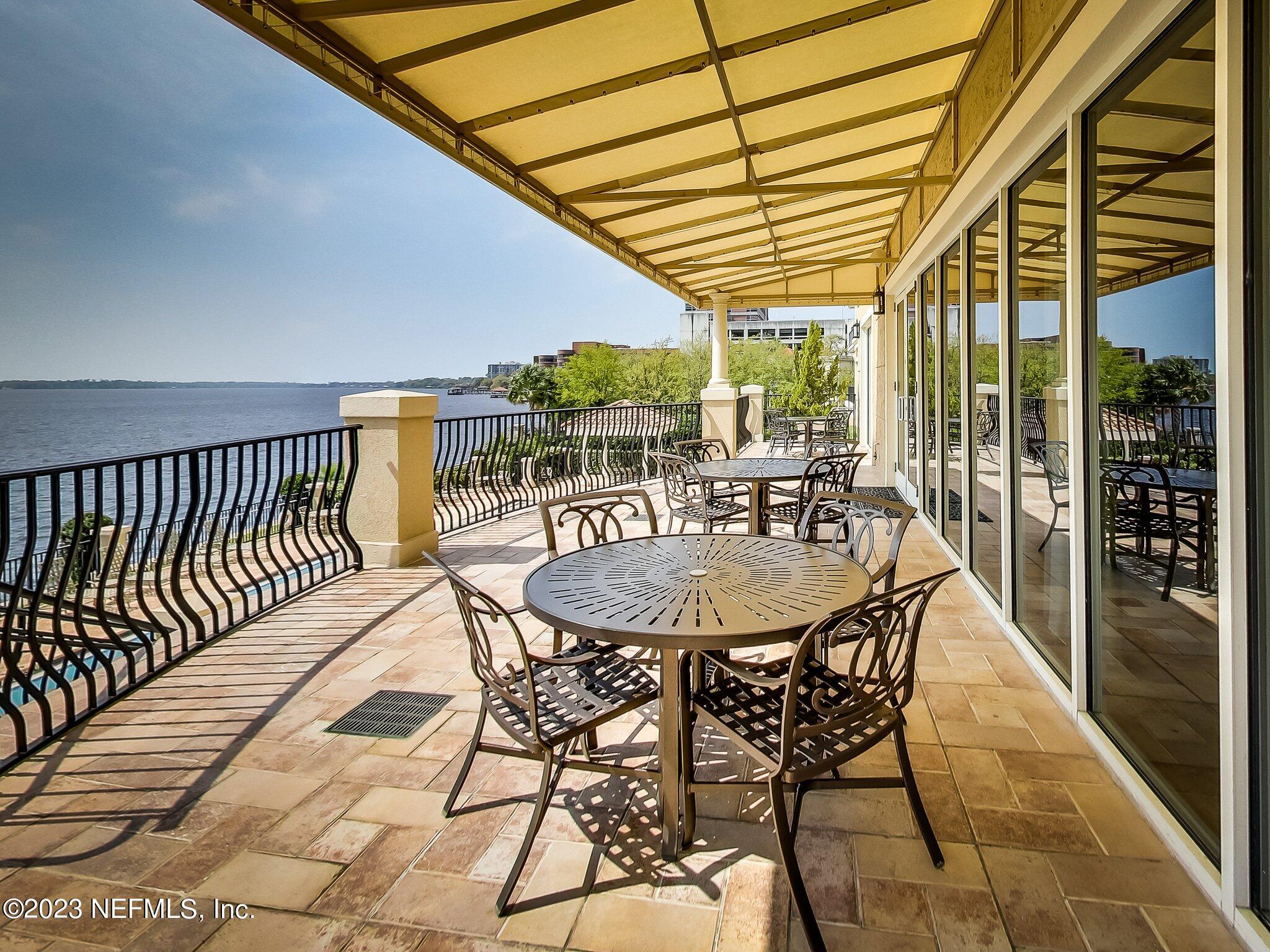 2358 Riverside Avenue, Unit 406 Jacksonville, FL 32204 - Photo 39 of 54 a view of a patio with a table and chairs and floor to ceiling window with wooden fence