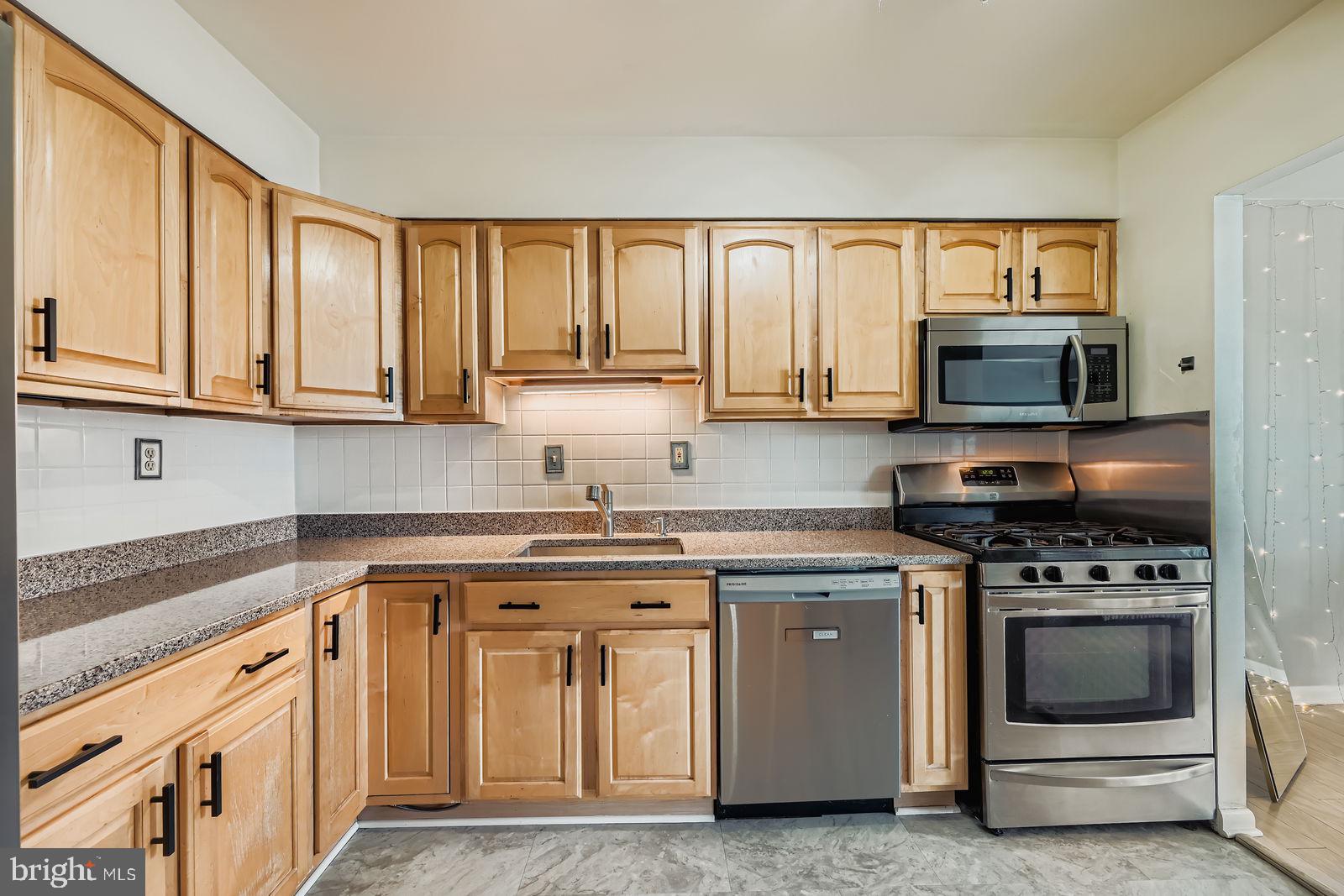 9900 Georgia Avenue, Unit 27716 Silver Spring, MD 20902 - Photo 17 of 37 a kitchen with stainless steel appliances granite countertop a stove a sink and a microwave