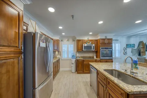 a kitchen with stainless steel appliances granite countertop a sink a stove and a wooden cabinets