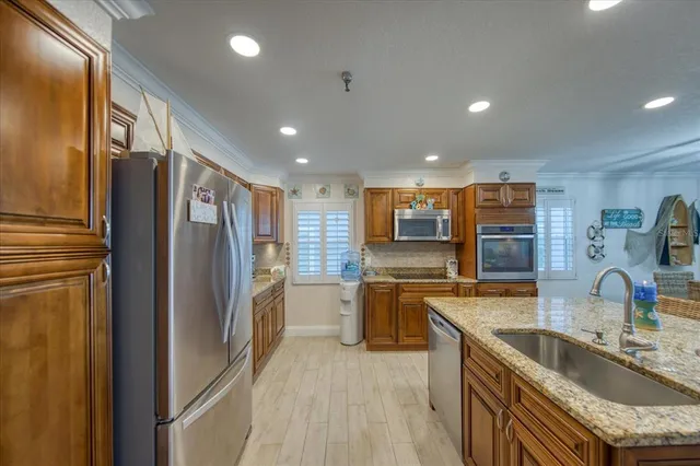 a kitchen with stainless steel appliances granite countertop a sink a stove and a wooden cabinets