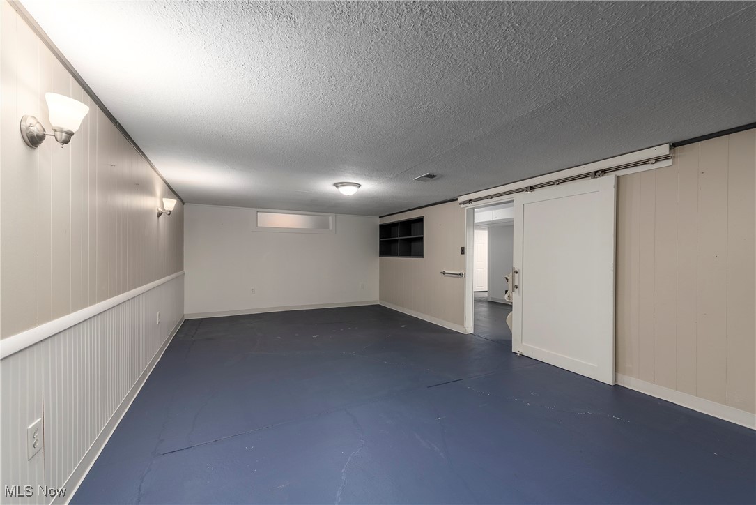 7717 Hoertz Road Cleveland, OH 44134 - Photo 35 of 49 Basement featuring a barn door and a textured ceiling