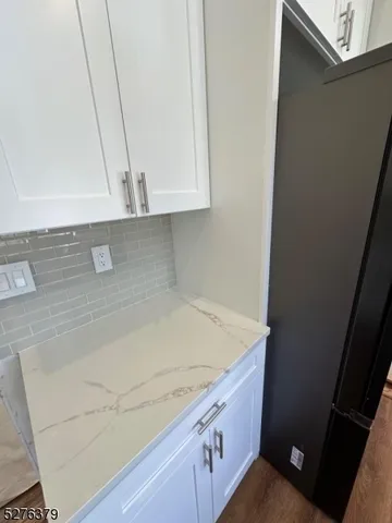 a kitchen with granite countertop white cabinets and black appliances