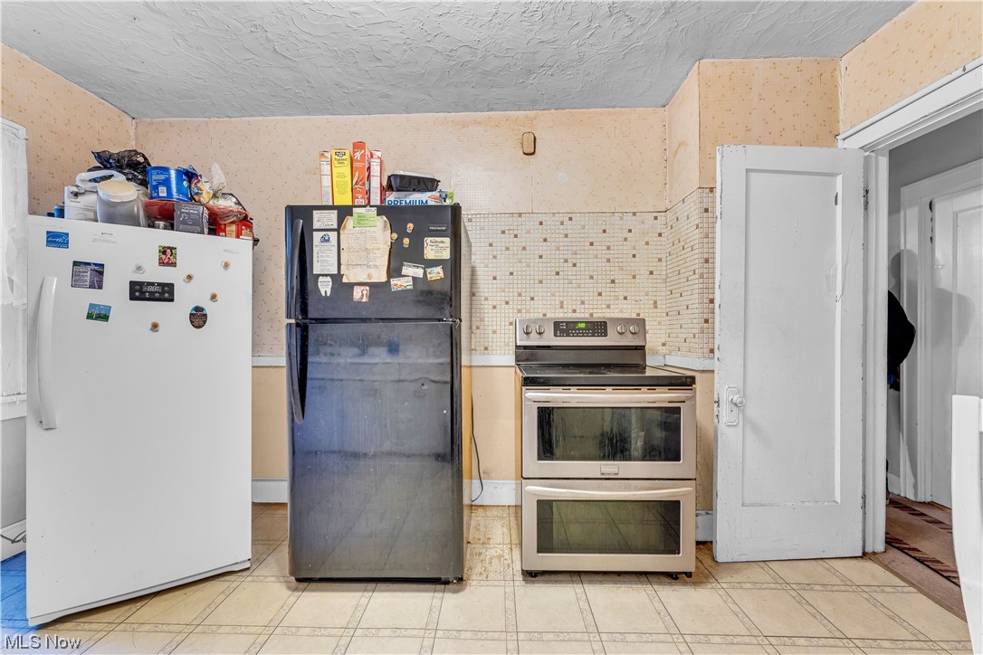 3550 Bosworth Road Cleveland, OH 44111 - Photo 20 of 43 Kitchen with double oven range, white fridge, light tile floors, and black refrigerator
