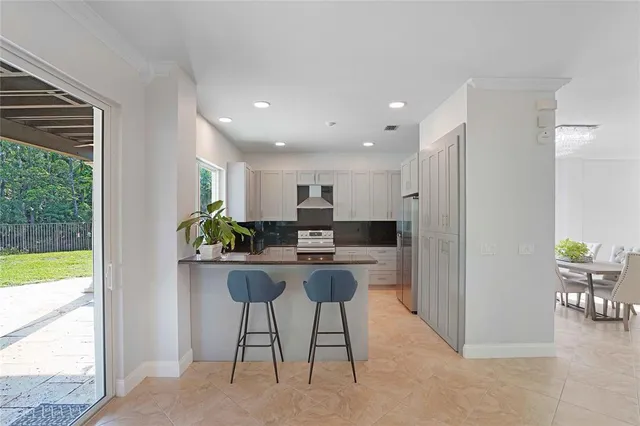 a kitchen with stainless steel appliances kitchen island granite countertop a refrigerator a stove a dining table and chairs