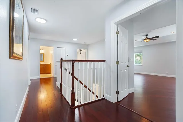 an empty room with wooden floor ceiling fan and windows