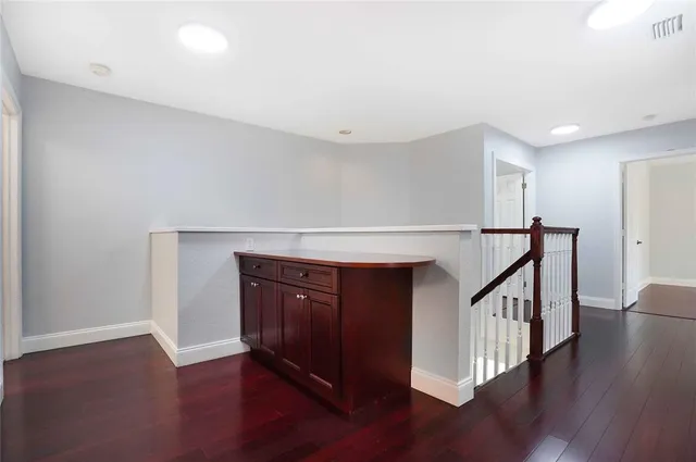 a view of an empty room with wooden floor and a ceiling fan