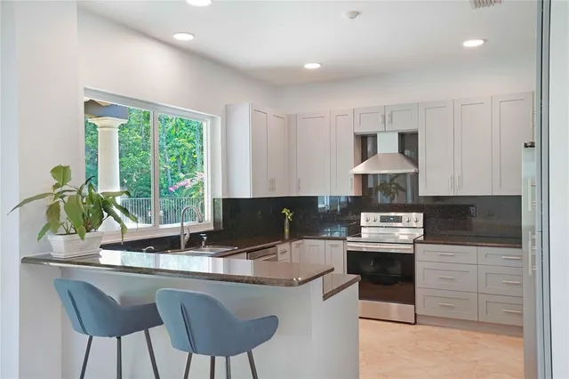 a kitchen with stainless steel appliances granite countertop a stove a sink and a refrigerator