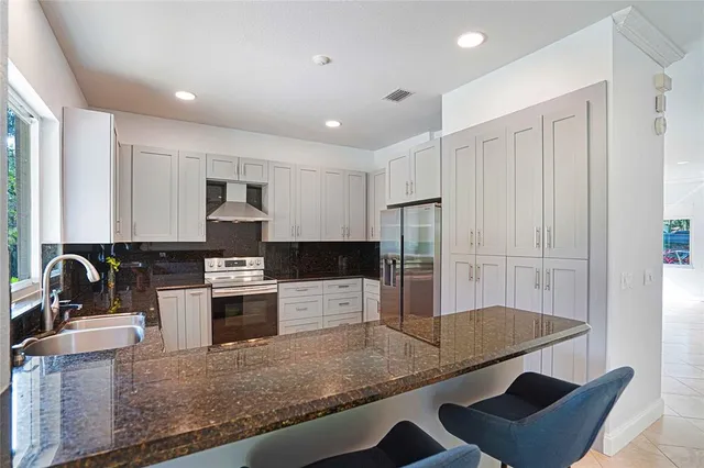 a kitchen with stainless steel appliances granite countertop a sink a stove and a refrigerator