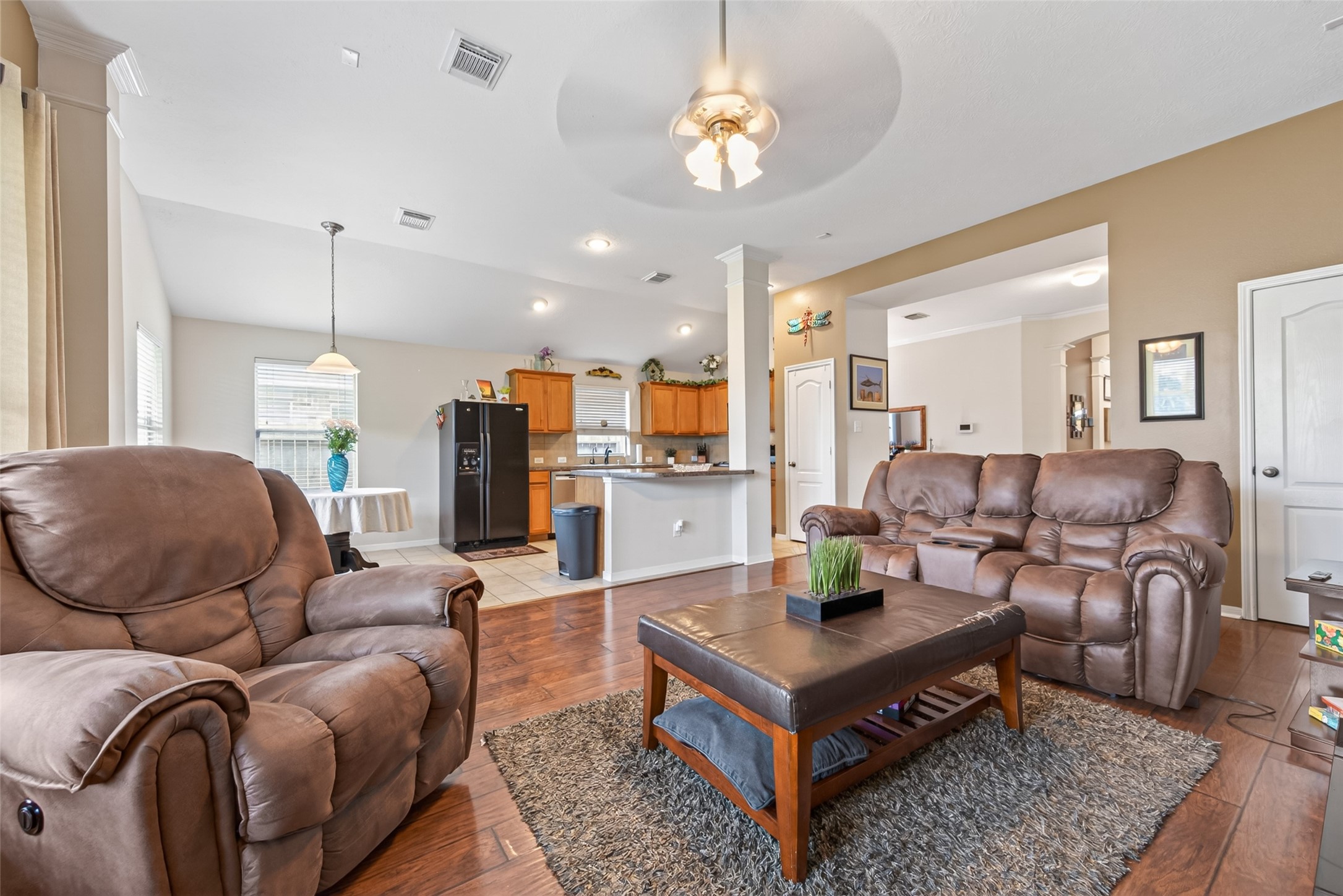 8622 Henrico Lane Rosenberg, TX 77469 - Photo 3 of 20 This inviting open-concept living area features cozy leather seating, warm wood flooring, and a modern kitchen with a central island. Perfect for relaxation and entertaining.