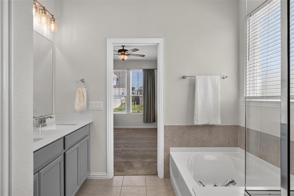 8715 Royal Star Road Rowlett, TX 75089 - Photo 9 of 39 Dual vanity with undermount sinks and chrome fixtures, built-in bathtub, glass shower enclosure, and tiled flooring