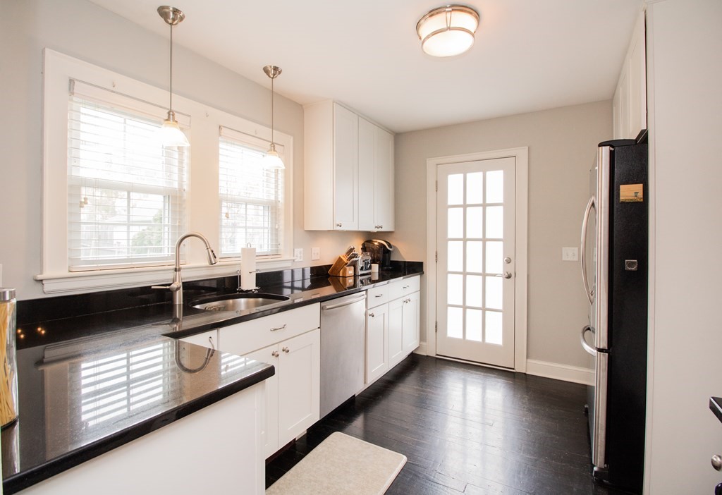 66 Howitt Road Boston, MA 02132 - Photo 1 of 24 a kitchen with granite countertop a stove a sink and white cabinets with wooden floor