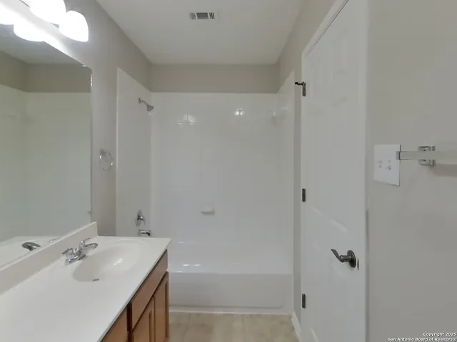 a bathroom with a tub sink vanity and mirror