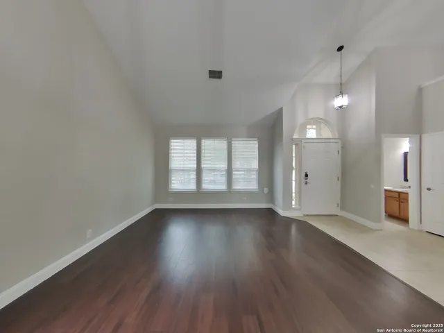 a view of an empty room with window and wooden floor
