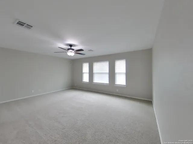 an empty room with a ceiling fan and window