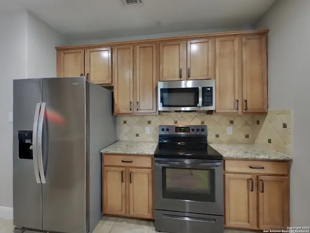 a kitchen with granite countertop white cabinets and stainless steel appliances