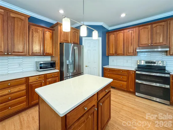 a kitchen with stainless steel appliances a stove a refrigerator a sink dishwasher and wooden cabinets with wooden floor
