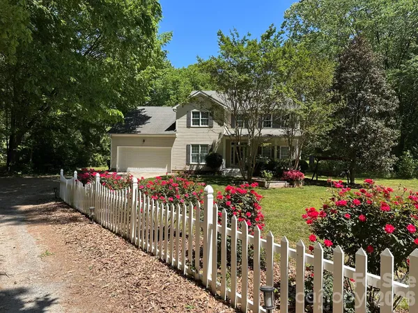 a front view of house with flower garden and wooden fence