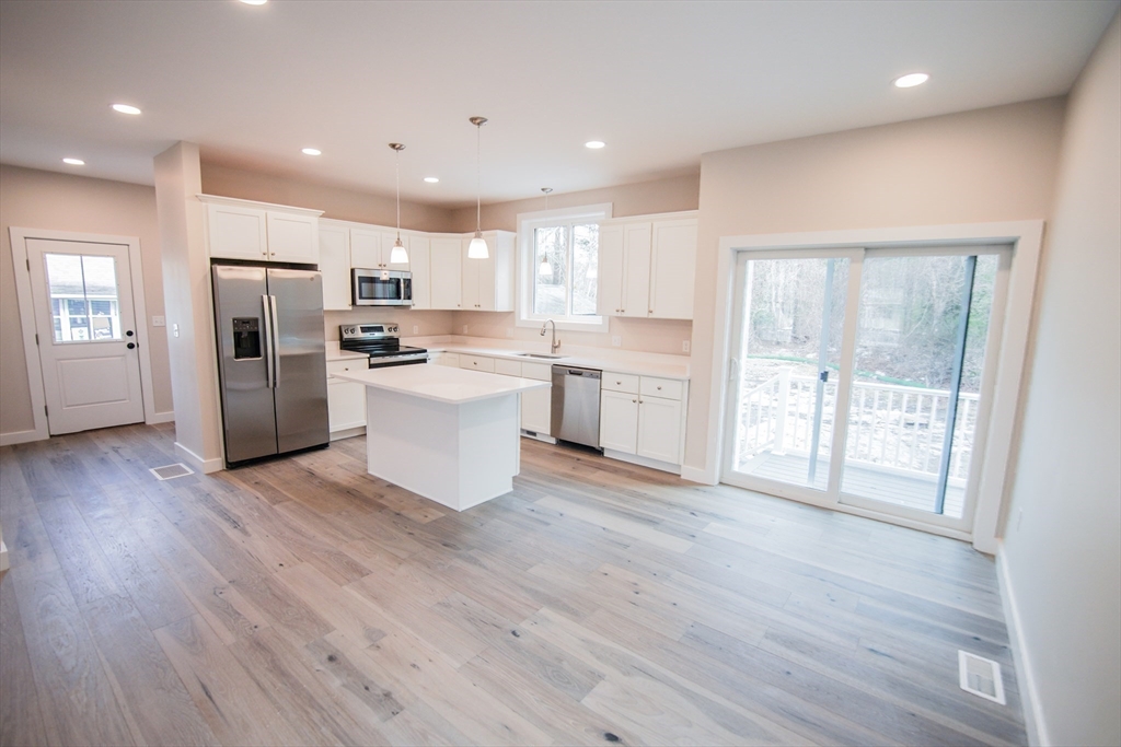 a large kitchen with a wooden floor and stainless steel appliances