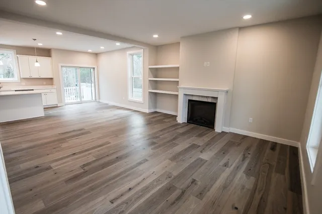 an empty room with wooden floor fireplace and windows