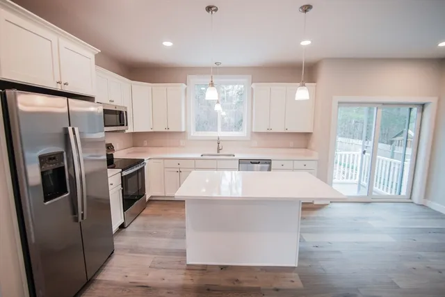 a large kitchen with stainless steel appliances granite countertop a sink a stove a refrigerator with grey cabinets